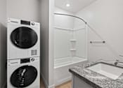 Thumbnail 32 of 55 - A modern laundry room with a washer and dryer stacked on top of each other.