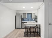 Thumbnail 49 of 61 - a kitchen with a island and stools and a stainless steel refrigerator at AVIA Lofts on Liberty Ridge, Florida, 32256