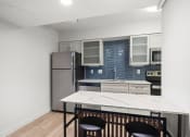 Thumbnail 47 of 61 - a kitchen with a white island and a stainless steel refrigerator at AVIA Lofts on Liberty Ridge, Florida, 32256