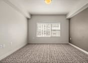 Thumbnail 52 of 71 - an empty room with a large window and a carpeted floor at Wilmington Flats Apartments, Utah