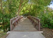 Thumbnail 71 of 71 - a wooden bridge over a river with trees on both sides at Wilmington Flats Apartments, Utah, 84106