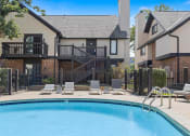 Thumbnail 15 of 50 - a swimming pool with chairs and a house in the background