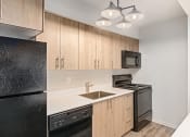 Thumbnail 49 of 50 - a kitchen with black appliances and wooden cabinets