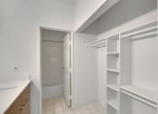 Thumbnail 48 of 51 - a walk in closet with white shelving and a door to a bathroom