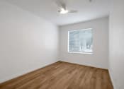 Thumbnail 45 of 51 - a bedroom with white walls and wood floors and a window