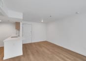 Thumbnail 42 of 51 - a living room and kitchen with white walls and wood floors