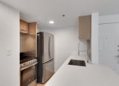 Thumbnail 29 of 51 - a kitchen with a white counter top and a stainless steel refrigerator