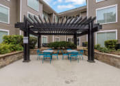 Thumbnail 27 of 51 - a patio with blue tables and chairs under a wooden pergola