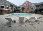 Thumbnail 24 of 51 - an apartment building with a swimming pool and chairs