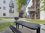 Thumbnail 31 of 56 - a picnic area with two benches and a grill in front of an apartment building