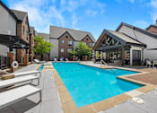Thumbnail 4 of 56 - A large swimming pool surrounded by a patio and buildings.