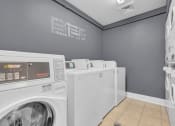 Thumbnail 34 of 61 - washing machines and dryers in a laundry room with a gray wall and gray walls at AVIA Lofts on Liberty Ridge, Jacksonville, FL, 32256