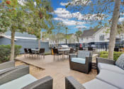 Thumbnail 44 of 61 - an outdoor patio with tables and chairs and trees at AVIA Lofts on Liberty Ridge, Jacksonville, FL