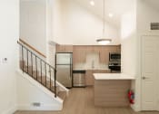 Thumbnail 20 of 34 - a white kitchen with a staircase and a stainless steel refrigerator
