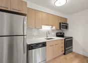 Thumbnail 40 of 92 - an empty kitchen with stainless steel appliances and wooden cabinets at AVIA Lofts on Parkway Apartments, Vancouver, WA, 98662