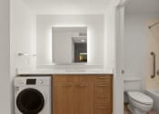 Thumbnail 55 of 92 - a bathroom with a washing machine and a sink and a mirror at AVIA Lofts on Parkway Apartments, Washington, 98662
