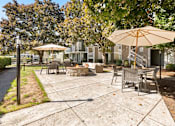 Thumbnail 35 of 92 - A sunny day at the park with a picnic table and chairs under an umbrella.