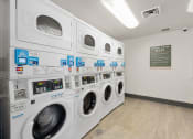 Thumbnail 30 of 92 - a washer and dryer machine in a laundry room with other washing machines at AVIA Lofts on Parkway Apartments, Washington, 98662