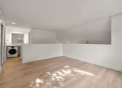 Thumbnail 61 of 92 - the living room and laundry room of a renovated house with white walls and wood floors at AVIA Lofts on Parkway Apartments, Washington, 98662