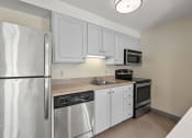 Thumbnail 37 of 92 - a kitchen with stainless steel appliances and white cabinets at AVIA Lofts on Parkway Apartments, Vancouver