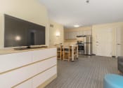 Thumbnail 91 of 108 - a living room with a television and a kitchen with a table and chairs