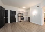 Thumbnail 76 of 108 - an empty living room and kitchen with a wood floor and black doors