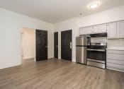 Thumbnail 77 of 108 - an empty living room with a kitchen with stainless steel appliances