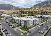 Thumbnail 17 of 136 - an aerial view of an apartment complex with mountains in the background at The Flats at Riverwoods, Provo