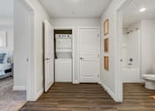 Thumbnail 120 of 136 - a hallway with a toilet and a washer and dryer in a white room at The Flats at Riverwoods, Provo, UT, 84604