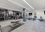 Thumbnail 83 of 136 - a gym with weights and cardio equipment in a room with a mural on the wall at The Flats at Riverwoods, Provo, Utah