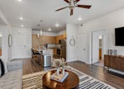 Thumbnail 111 of 136 - a living room with a couch and a table in front of a kitchen at The Flats at Riverwoods, Provo