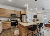 Thumbnail 38 of 136 - a kitchen with a marble counter top and an island with chairs at The Flats at Riverwoods, Provo, UT