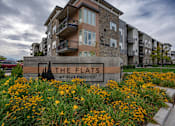 Thumbnail 1 of 136 - apartments sign in front of grass and flowers at The Flats at Riverwoods, Provo, Utah