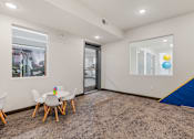 Thumbnail 68 of 136 - a play room with a table and chairs and a sliding glass door at The Flats at Riverwoods, Provo