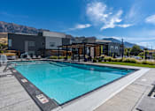Thumbnail 98 of 136 - a swimming pool with a building in the background and a blue sky at The Flats at Riverwoods, Provo, UT
