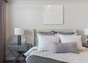Thumbnail 116 of 136 - a bedroom with a bed and pillows and a nightstand with a lamp and at The Flats at Riverwoods, Provo, UT, 84604