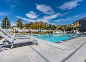 Thumbnail 100 of 136 - pool and lounge chairs with mountains in the background at The Flats at Riverwoods, Provo, Utah