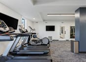 Thumbnail 87 of 136 - the gym has cardio equipment and a flat screen tv at The Flats at Riverwoods, Provo, UT, 84604