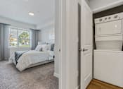 Thumbnail 117 of 136 - a bedroom with a bed and a washer and dryer next to a closet at The Flats at Riverwoods, Provo, Utah