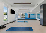 Thumbnail 78 of 136 - a fitness room with yoga mats and a wall mural of mountains at The Flats at Riverwoods, Provo, Utah