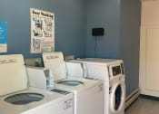 Thumbnail 16 of 34 - a laundry room with four washers and a dryer
