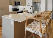 Thumbnail 56 of 144 - A kitchen with a white counter top and wooden chairs.