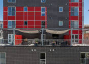 Thumbnail 109 of 131 - the back of a brick building with red doors and a balcony at Paperbox Lofts, Utah, 84101
