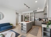 Thumbnail 14 of 131 - a living area with a kitchen and a blue couch at Paperbox Lofts, Salt Lake City, Utah
