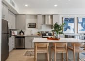Thumbnail 2 of 131 - a kitchen with stainless steel appliances and an island with four chairs at Paperbox Lofts, Salt Lake City, UT