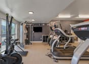 Thumbnail 113 of 131 - a gym with various exercise machines and a tv at Paperbox Lofts, Salt Lake City