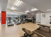 Thumbnail 43 of 131 - a gym with cardio machines and weights on a wooden floor at Paperbox Lofts, Salt Lake City, Utah