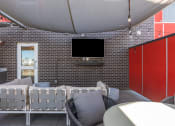 Thumbnail 119 of 131 - a patio with chairs and a television on a brick wall at Paperbox Lofts, Salt Lake City, UT, 84101