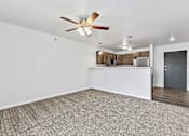 Thumbnail 17 of 74 - a bedroom with a ceiling fan and a kitchen in the background at Red Rock Apartments, South Dakota