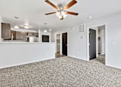 Thumbnail 16 of 74 - a living room with a ceiling fan and a kitchen in the background at Red Rock Apartments, South Dakota 57702